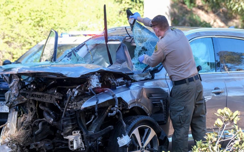 A law enforcement officer looks over a damaged vehicle following a rollover accident involving golfer Tiger Woods in the Rancho Palos Verdes suburb of Los Angeles - AP