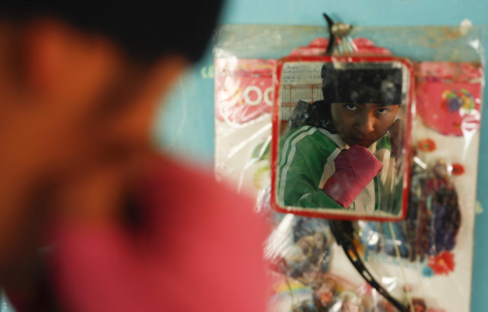 Gracce Kelly Flores, a 12-year-old boxer who goes by the nickname Hands of Stone, strikes a pose in the mirror hanging in her kitchen after her morning workout in Palca, Bolivia, early Thursday, June 10, 2021. At age 8, Flores defeated a 10-year-old boy, and with three national boxing medals under her belt, she dreams of reaching the women's boxing world championship. (AP Photo/Juan Karita)