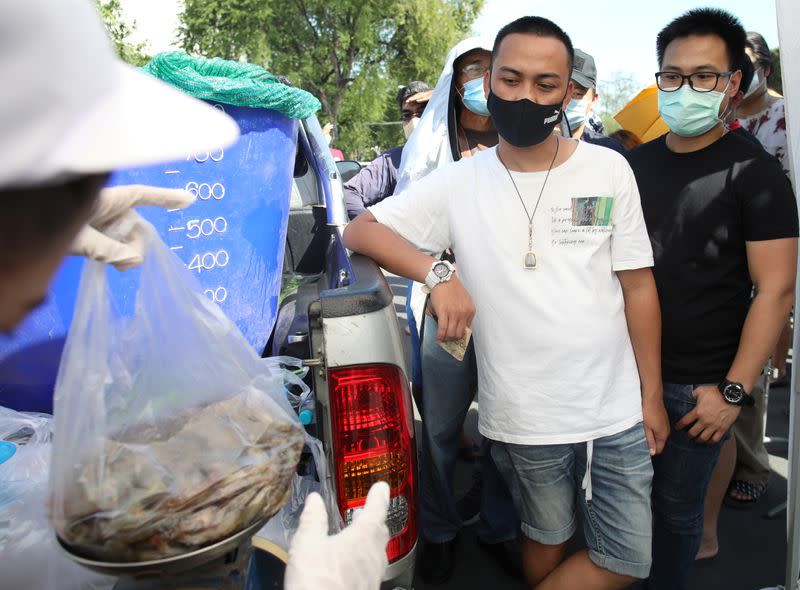 People wait to buy shrimps from anti government protesters selling shrimps in front of government house amidst the COVID-19 outbreak in Bangkok