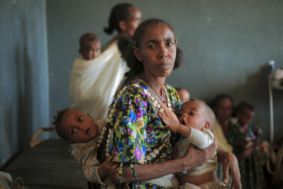 Ada Arae Girmay, 40, holds her babies Assefa and Metkel, 12 months-old twins, who are suffering from malnutrition, at the Finarwa Health Center in Nebar Hadnet, in the Tigray region of northern Ethiopia, on Tuesday, Feb. 27, 2024. (AP Photo/Amir Aman Kiyaro)