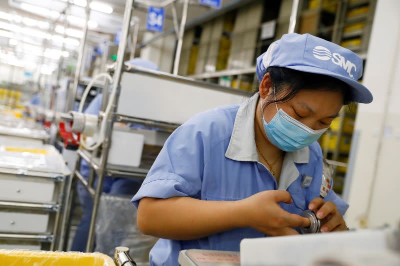 FILE PHOTO: An employee wearing a face mask works at a factory of the component maker SMC during a government organised tour of its facility following the outbreak of the coronavirus disease (COVID-19), in Beijing