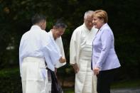 German Chancellor Angela Merkel (R) is welcomed by Shinto priests as she arrives at Ise-Jingu Shrine in the city of Ise on the first day of the G7 leaders summit