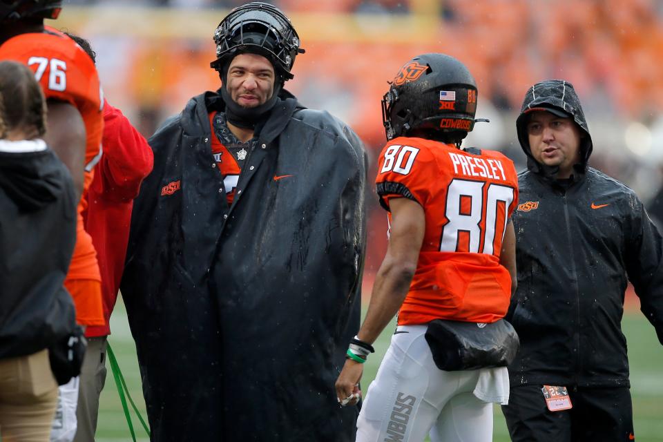 Oklahoma State quarterback Spencer Sanders, who didn't play Saturday, talks with receiver Brennan Presley (80).