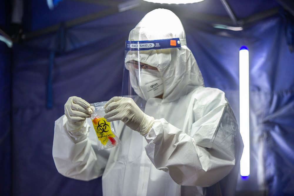 A health worker puts a test tube into biohazard plastic after collecting a sample for Covid-19 testing in Jalan Pudu, Kuala Lumpur January 18, 2021. — Picture by Shafwan Zaidon