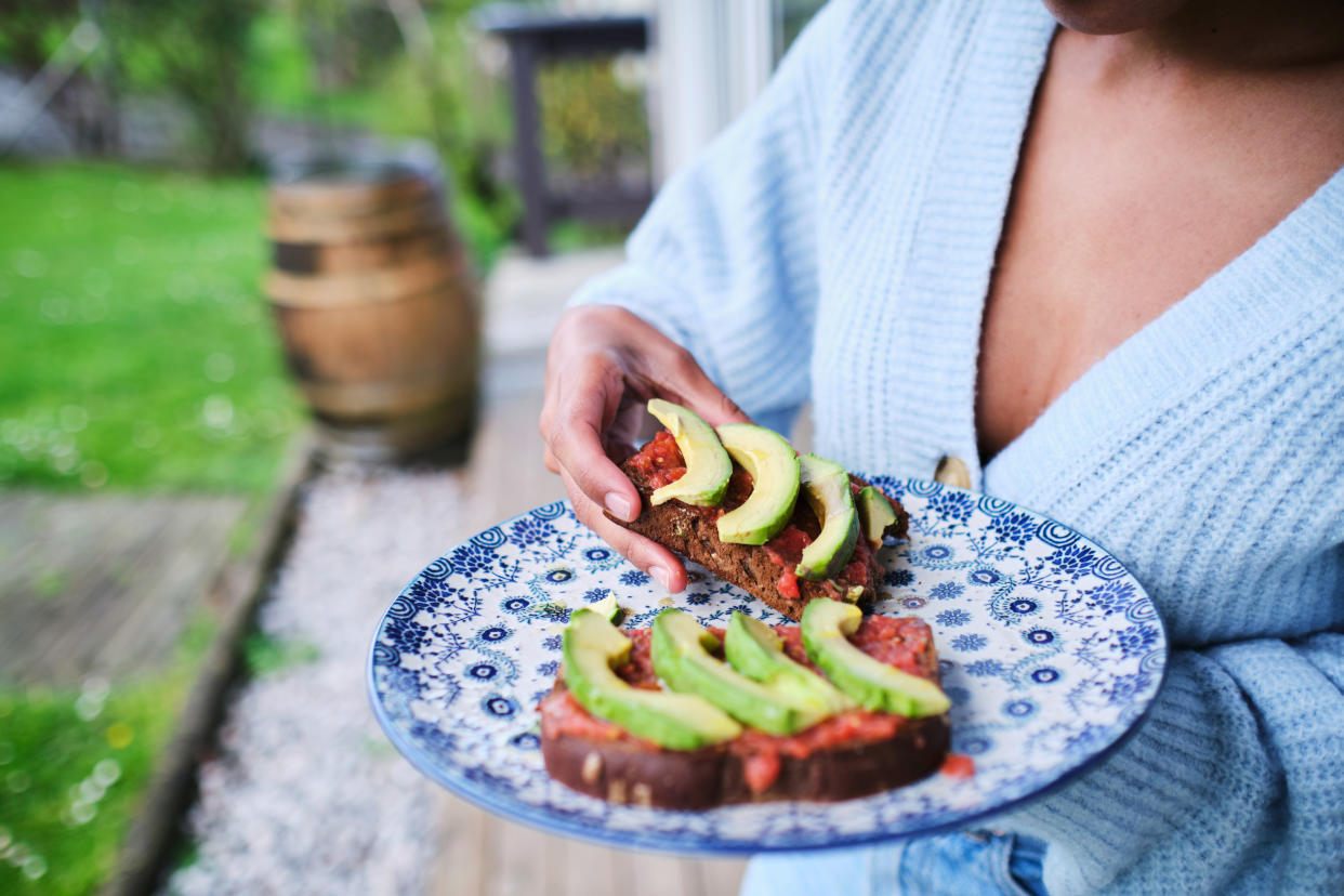 close-up shot of an unrecognizable person holding a plate of avocado and tomato toast food pairing