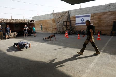 An Israeli instructor walks near tourists as they take part in a two hour "boot camp" experience, at "Caliber 3 Israeli Counter Terror and Security Academy" in the Gush Etzion settlement bloc south of Jerusalem in the occupied West Bank July 13, 2017. Picture taken July 13, 2017. REUTERS/Nir Elias