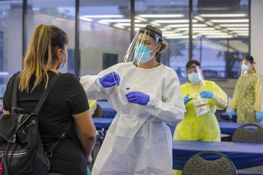 ONTARIO, CA -JULY24: San Bernardino County Health Department LVN Elizabeth McKinnon explains how to self-swab for COVID-19 test to Glenda Guerra at a coronavirus testing site at Ontario Convention Center. Ontario Convention Center on Friday, July 24, 2020 in Ontario, CA. (Irfan Khan/Los Angeles Times)