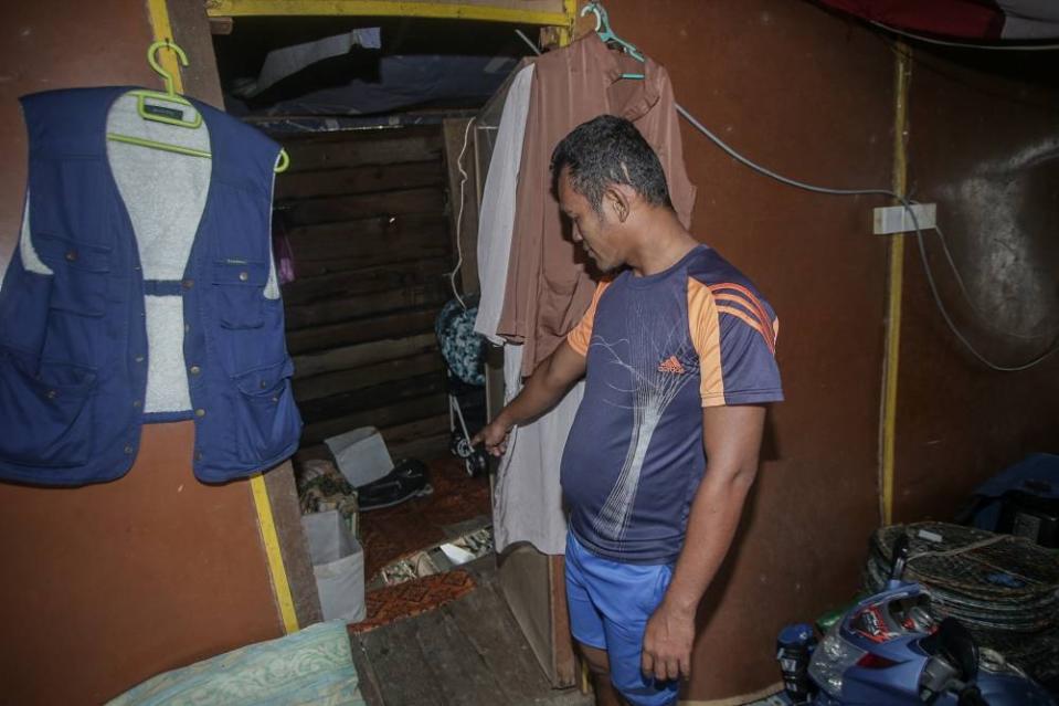 Fisherman Muhammad Haidi Zakaria points towards a crooked wooden floor in a room that he used to sleep in. — Picture by Farhan Najib