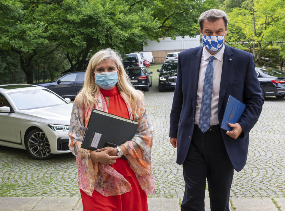 Melanie Huml, Health Minister of the German state of Bavaria, left, and Bavaria's governor Markus Soeder, right, arrive for a joint press conference in Munich, Germany, Thursday, Aug. 13, 2020. (Peter Kneffel/dpa via AP)