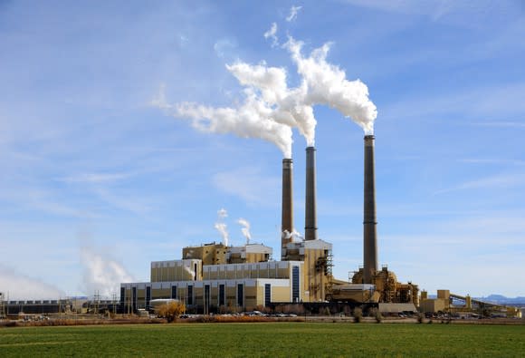 A power factory with smokes coming out of three smokestacks.