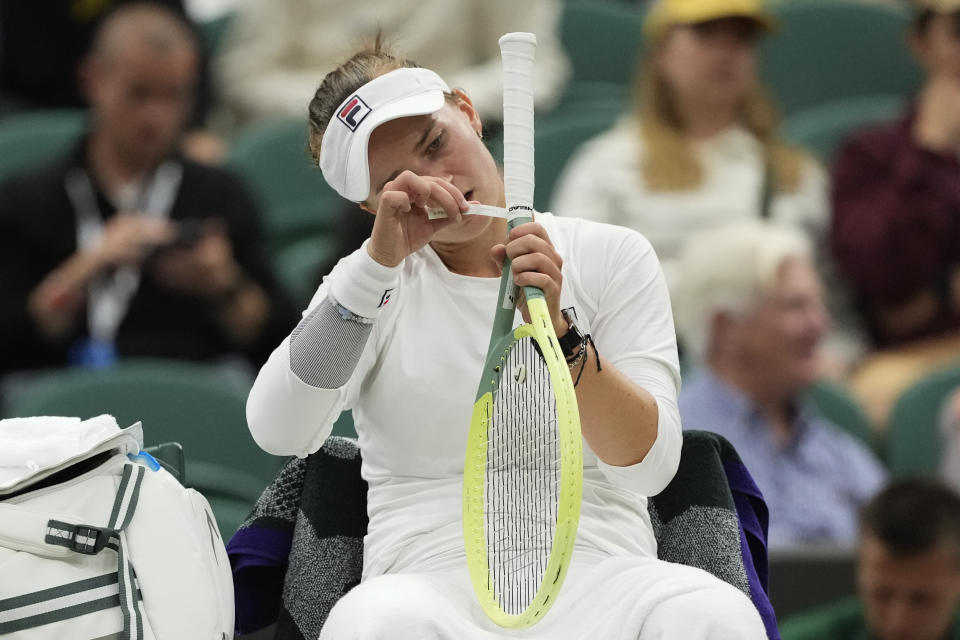Barbora Krejcikova of the Czech Republic puts tape around her racket handle during her fourth round match against Danielle Collins of the United States at the Wimbledon tennis championships in London, Monday, July 8, 2024. (AP Photo/Alberto Pezzali)