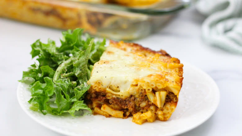 slice of mac and cheese lasagna with greens on the side