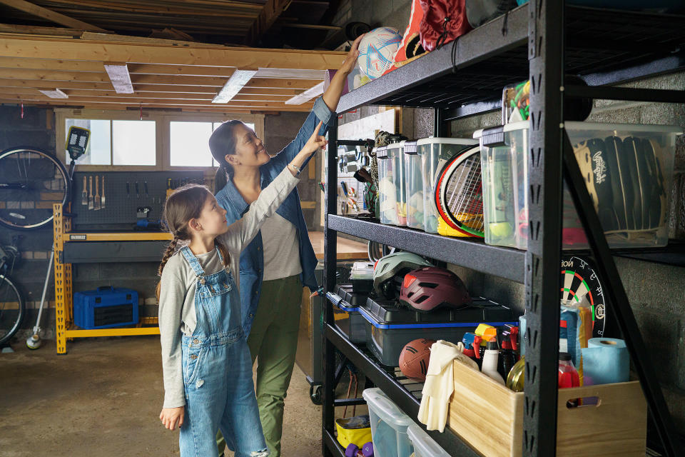 Woman reaching to get sports equipment down from a garage shelving unit for her kid