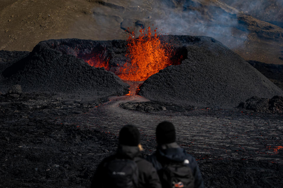 Tourists visit a heart shaped crater as lava flows from the volcano in Fagradalsfjall, Iceland, following an eruption from a new fissure on the Reykjanes Peninsula, around 35 miles from the capital city of Reykjavic, the eruption has been ongoing since the 3rd August 2022. Picture date: Monday August 15, 2022. (Photo by Aaron Chown/PA Images via Getty Images)