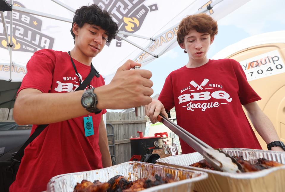 Marc Crotta, left, and Matthew Wolfe, high school sophomores from Georgia and members of the Junior Pitmasters, prepare hot wings as they compete on a team with famed competition barbecue pitmaster Melissa Cookston. Their crew, the Tallulah Falls Pit Vipers, were the winners of the World Junior BBQ League Championship.