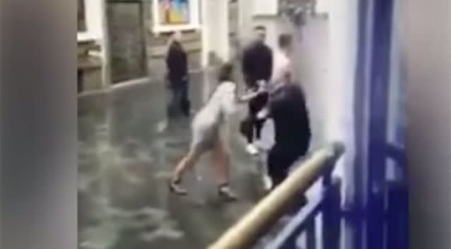 The bouncer can be seen in this photo ducking to avoid being struck by the woman. Source: Twitter