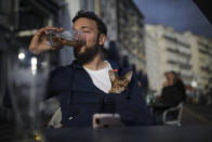Naguey drinks a final beer with his cat Nela before bars and restaurants close, in Marseille, southern France, Sunday Sept. 27, 2020. As restaurants and bars in Marseille prepared Sunday to shut down for a week as part of scattered new French virus restrictions, Health Minister Olivier Veran insisted that the country plans no fresh lockdowns. (AP Photo/Daniel Cole)