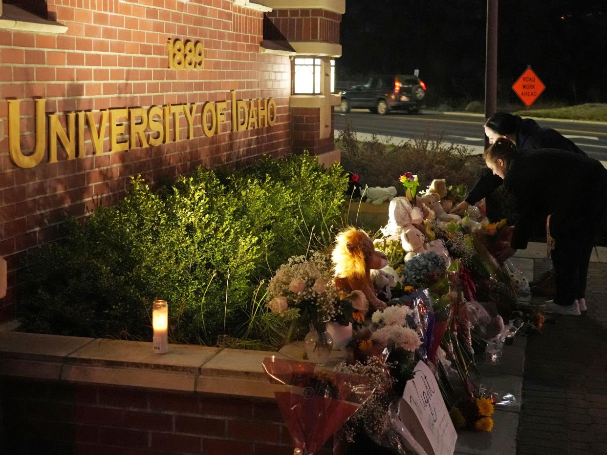 Two people place flowers at a growing memorial in front of a campus entrance sign for the University of Idaho, Wednesday, Nov. 16, 2022, in Moscow, Idaho.