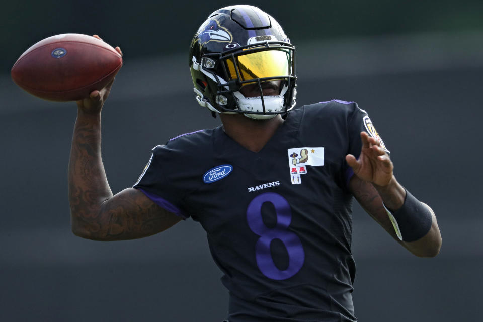  Lamar Jackson throws a pass during training camp while wearing a black training camp jersey and helmet.