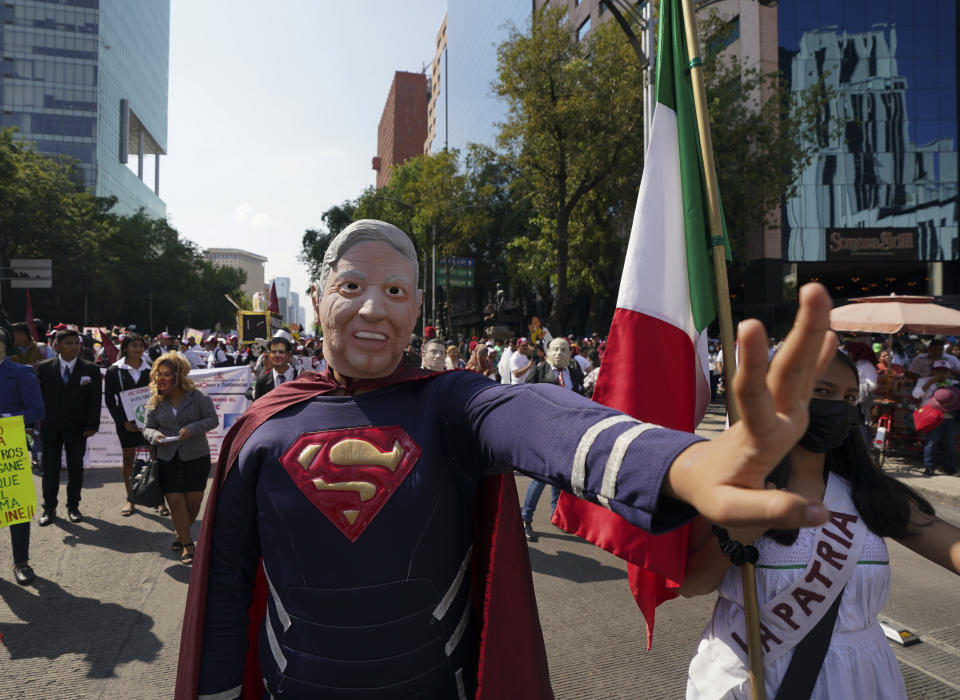 A man wears a mask with the visage of Mexican President Andres Manuel Lopez Obrador during a march in support of his administration, in Mexico City, Sunday, Nov. 27, 2022. (AP Photo/Fernando Llano)