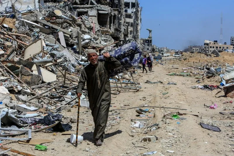 A Palestinian man carries items as Palestinians strive to salvage usable belongings amidst the rubble-strewn streets and buildings in Khan Yunis on Saturday Photo by Ismael Mohamad/UPI