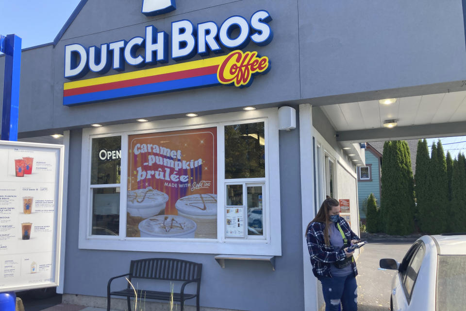 An employee of Dutch Bros Coffee in Salem, Ore., takes an order from a customer on Wednesday, Sept. 15, 2021. After humble beginnings as a pushcart operation decades ago in an Oregon town and growing into a company with hundreds of drive-thru coffee shops in about a dozen U.S. states, Dutch Bros Coffee on Wednesday launched an initial public offering on the New York Stock Exchange. (AP Photo/Andrew Selsky)