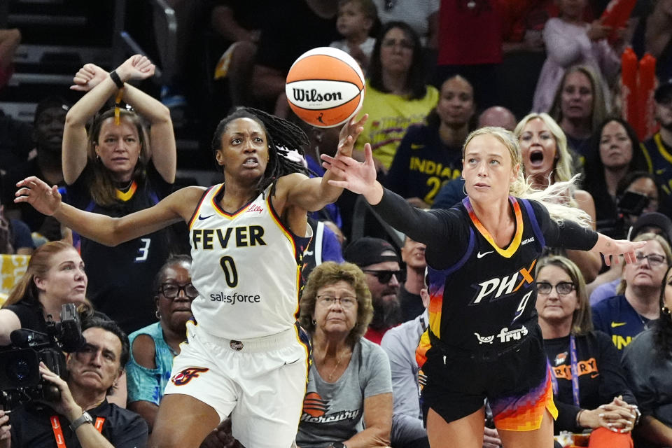 Indiana Fever guard Kelsey Mitchell (0) and Phoenix Mercury guard Sophie Cunningham (9) battle for a loose ball during the second half of a WNBA basketball game, Sunday, June 30, 2024, in Phoenix. (AP Photo/Ross D. Franklin)