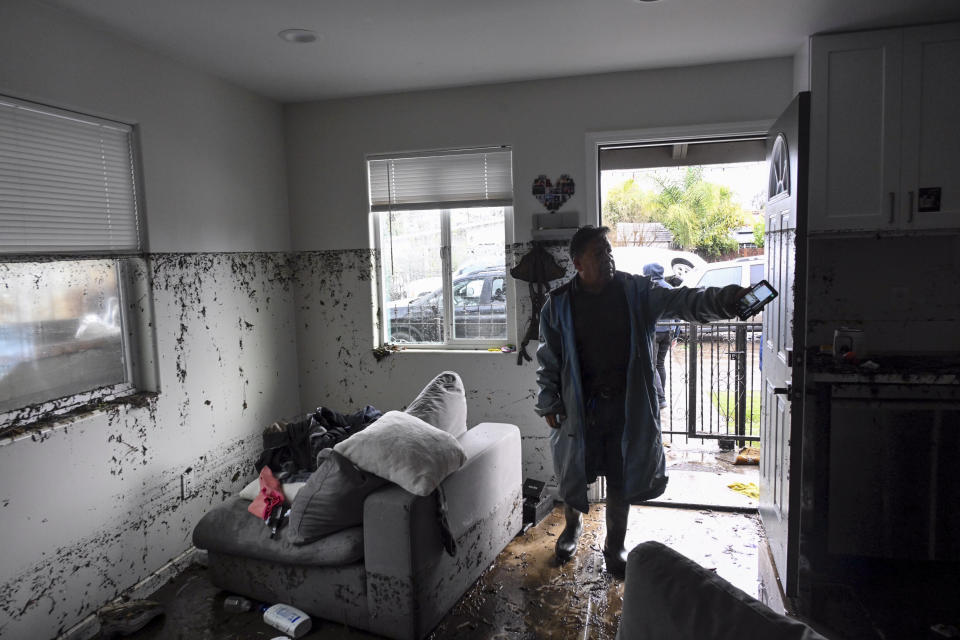 Tony Blas points to the water line inside his home that flooded during a rain storm Monday, Jan. 22, 2024, in San Diego. (AP Photo/Denis Poroy)