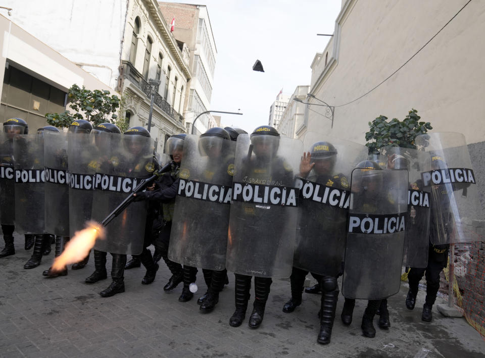 A police officer in riot gear fires his shotgun to disperse anti-government protesters who traveled to the capital from across the country to march against Peruvian President Dina Boluarte, as they clash in Lima, Peru, Thursday, Jan. 19, 2023. Protesters are seeking immediate elections, Boluarte's resignation, the release of ousted President Pedro Castillo and justice for up to 48 protesters killed in clashes with police. (AP Photo/Martin Mejia)