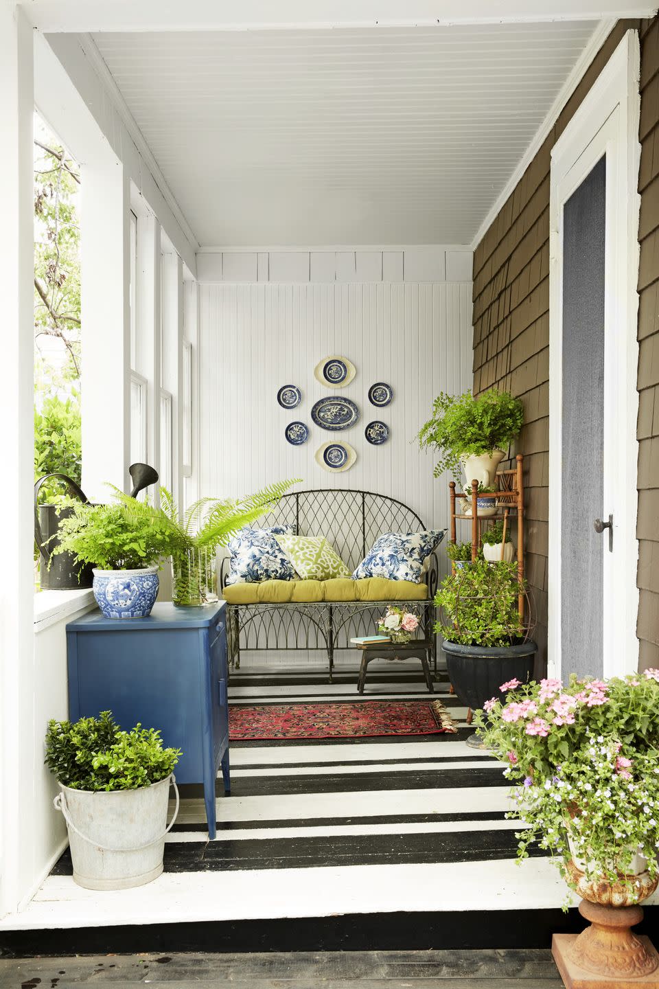 <p>A black-and-white striped treatment brings a graphic punch to this narrow porch floor. The simple color combo underfoot provides an anything-goes base for the eclectic mix of furniture, plants, and textiles.</p>