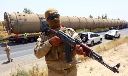 A Kurdish peshmerga fighter stands guard as new equipment arrives at Kalak refinery on the outskirts of Irbil, Iraq, Monday, July 14, 2014, as Kurdish authorities try to help ease the fuel shortage. Islamic militants have laid siege to Iraq's largest oil refinery in the city of Beiji. (AP Photo)