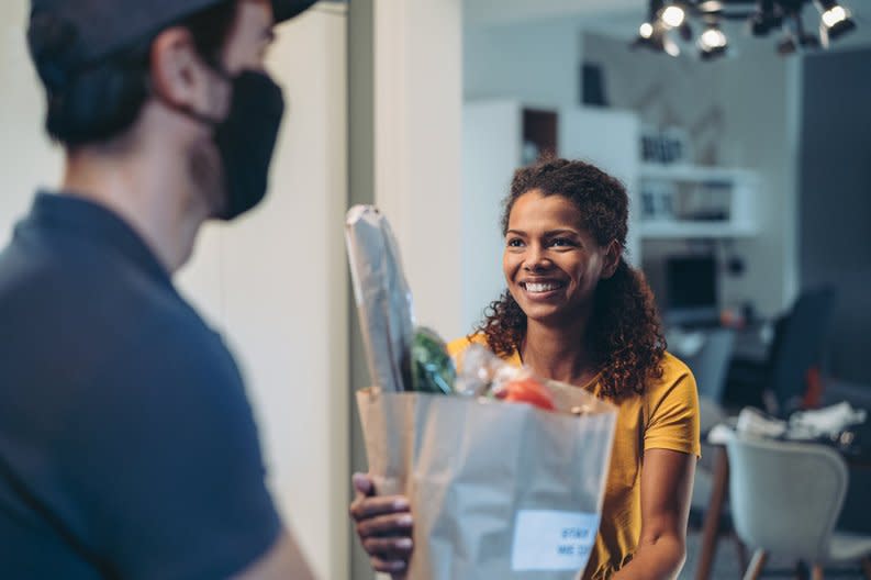 Woman accepting a delivery of groceries.