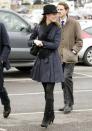 <p>Attending day four of the Cheltenham Horse Racing Festival in a black fedora and navy trench coat. </p>