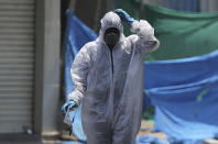 An Indian Disaster Response Force person walks after disinfecting a containment zone during lockdown to prevent the spread of new coronavirus in Hyderabad, India, Sunday, April 26, 2020. A month long restrictions in this country of 1.3 billion people have been eased somewhat by allowing neighborhood shops to reopen and manufacturing and farming activities to resume in rural areas to help millions of poor daily wage earners. (AP Photo/Mahesh Kumar A.)