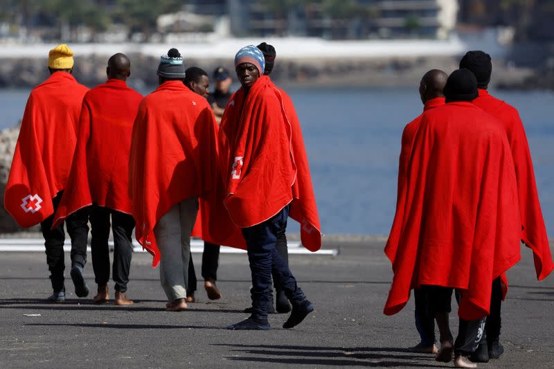 Migrants walk towards a Red Cross tent to be treated in the port of Arguineguin