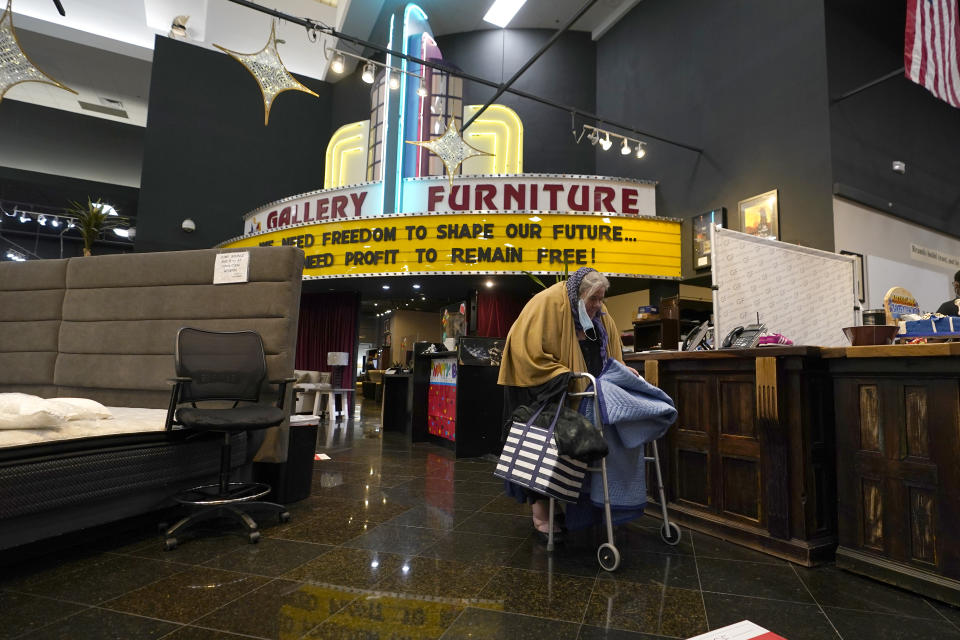 A woman walks past the front desk at a Gallery Furniture store which opened as a shelter for those in need of food, water and heat Wednesday, Feb. 17, 2021, in Houston. Millions in Texas still had no power after a historic snowfall and single-digit temperatures created a surge of demand for electricity to warm up homes unaccustomed to such extreme lows, buckling the state's power grid and causing widespread blackouts. (AP Photo/David J. Phillip)