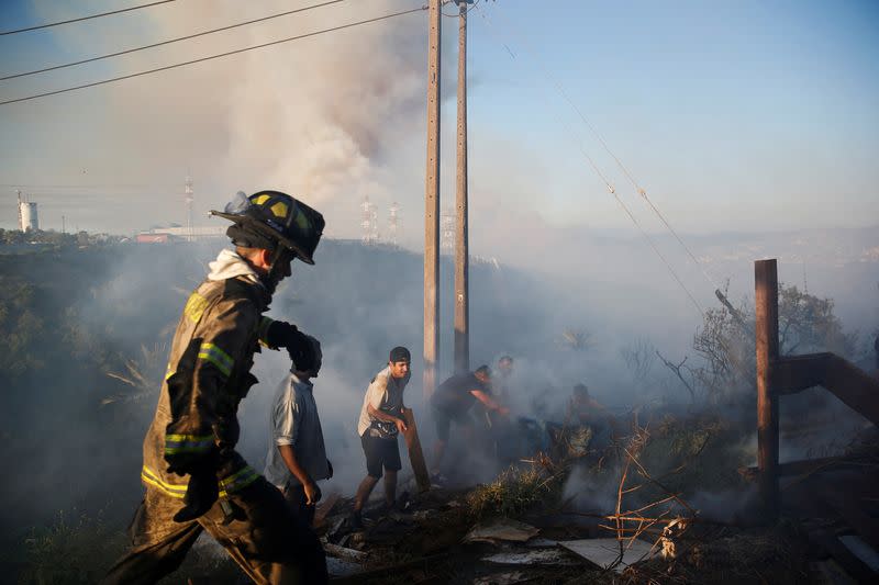 Residentes recogen escombros entre los restos de una casa quemada durante un incendio forestal en Viña del Mar, Chile