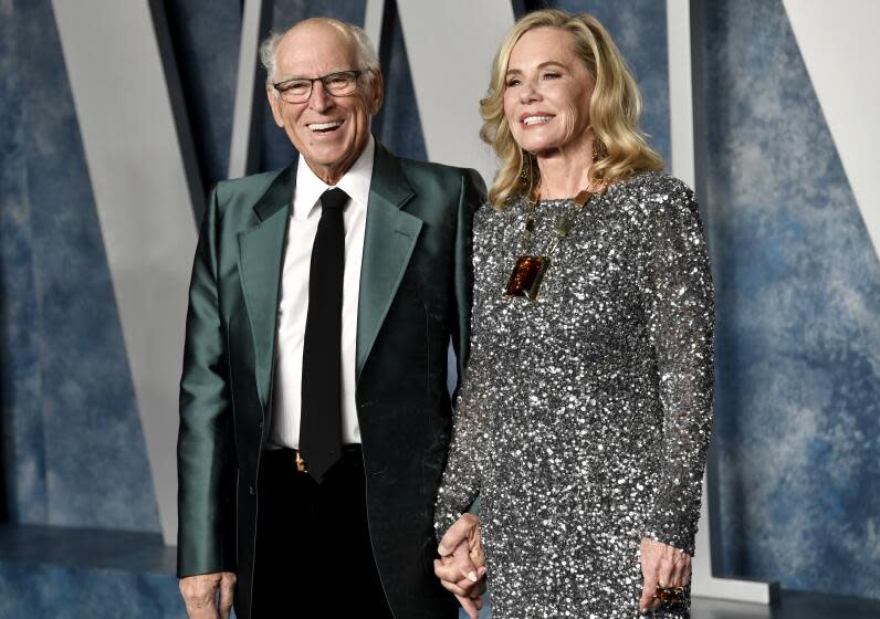 Jimmy Buffett, left, and his wife Jane Slagsvol hold hands at and smile at an Oscars party