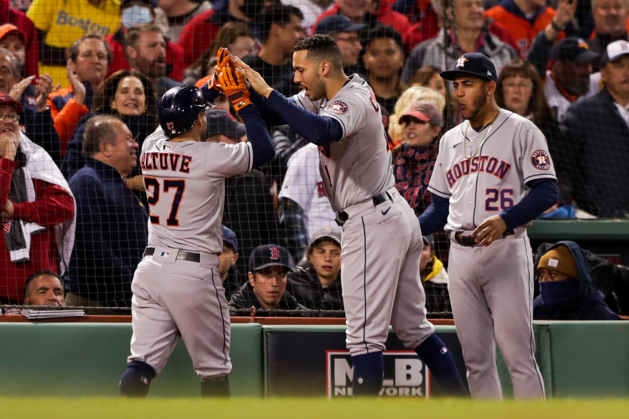 BOSTON, MA - OCTOBER 19: Jose Altuve #27 hi fives Carlos Correa #1 of the Houston Astros after scoring in the ninth inning during Game 4 of the ALCS between the Houston Astros and the Boston Red Sox at Fenway Park on Tuesday, October 19, 2021 in Boston, Massachusetts. (Photo by Mary DeCicco/MLB Photos via Getty Images)