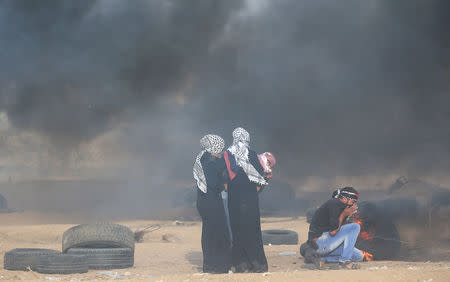 Palestinians react to tear gas fired by Israeli troops during a protest calling for lifting the Israeli blockade on Gaza and demanding the right to return to their homeland, at the Israel-Gaza border fence in the southern Gaza Strip October 5, 2018. REUTERS/Ibraheem Abu Mustafa