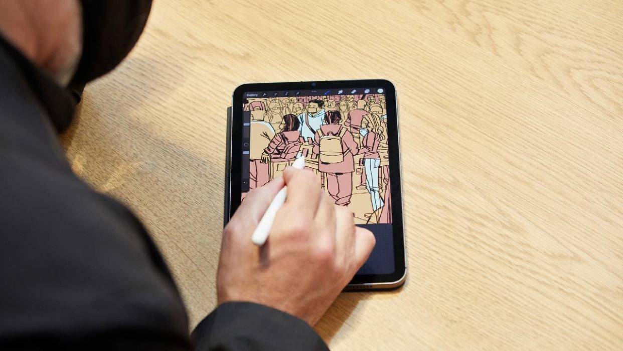  Apple iPad Mini (2021) on a wooden table. Someone is drawing on screen using an Apple Pencil. 