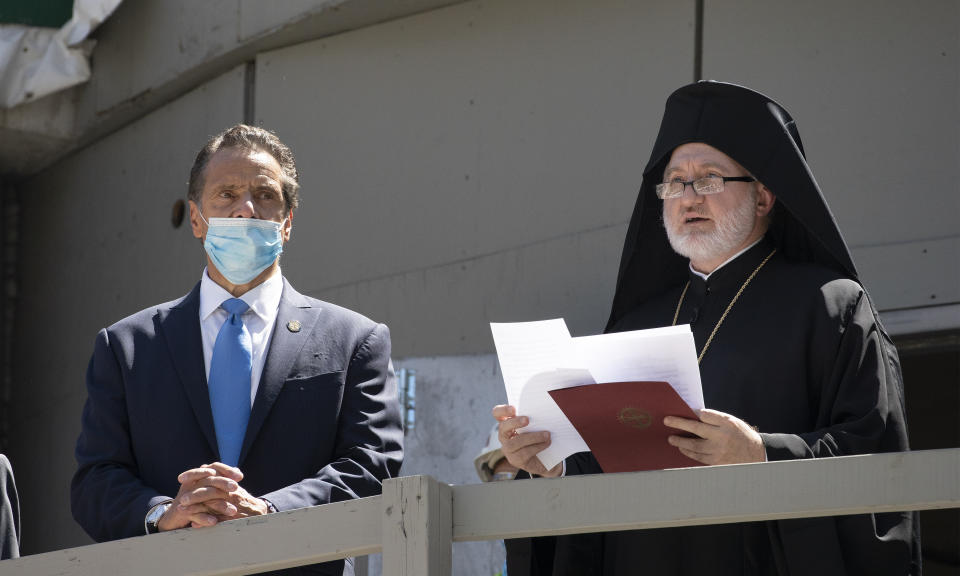 New York Gov. Andrew Cuomo, left, listens as Archbishop Elpidophoros of America delivers remarks during a ceremony at the St. Nicholas Greek Orthodox Church, Monday, Aug. 3, 2020 at the World Trade Center in New York. The original church was destroyed in the attacks of Sept. 11, 2001. The shrine is expected to open in 2021. (AP Photo/Mark Lennihan)