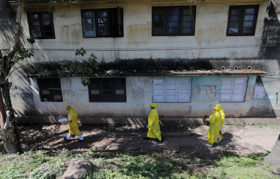 FILE- In this April 16, 2020 file photo, Sri Lankan police officials arrive to collect swab specimen from the suspected COVID-19 cases in a residential neighborhood during lockdown in Colombo, Sri Lanka. The government has announced that it will re-impose a 24-hour countrywide curfew from 8.00 pm Thursday until next Monday, as a part of the efforts to control the spreading of the virus. (AP Photo/Eranga Jayawardena, File)