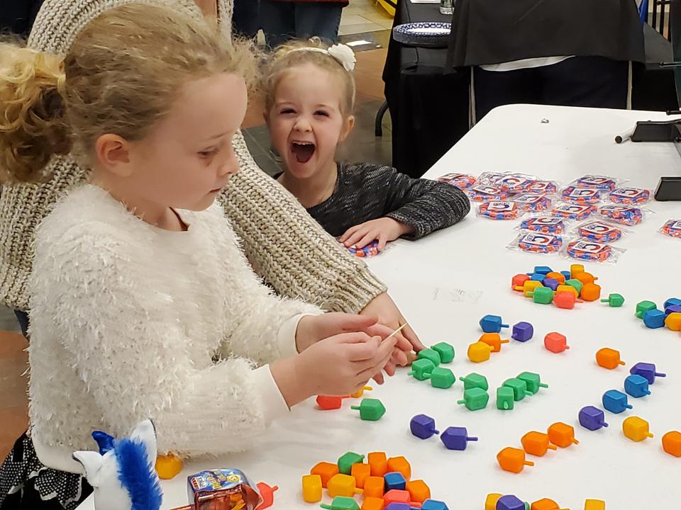 Rachel Nash, 6, of Exeter tried her hand at making dreidels. Her little sister Sofie, 4, apparently found this pretty funny at the Mall at Fox Run in Newington Sunday Nov. 28, 2021.