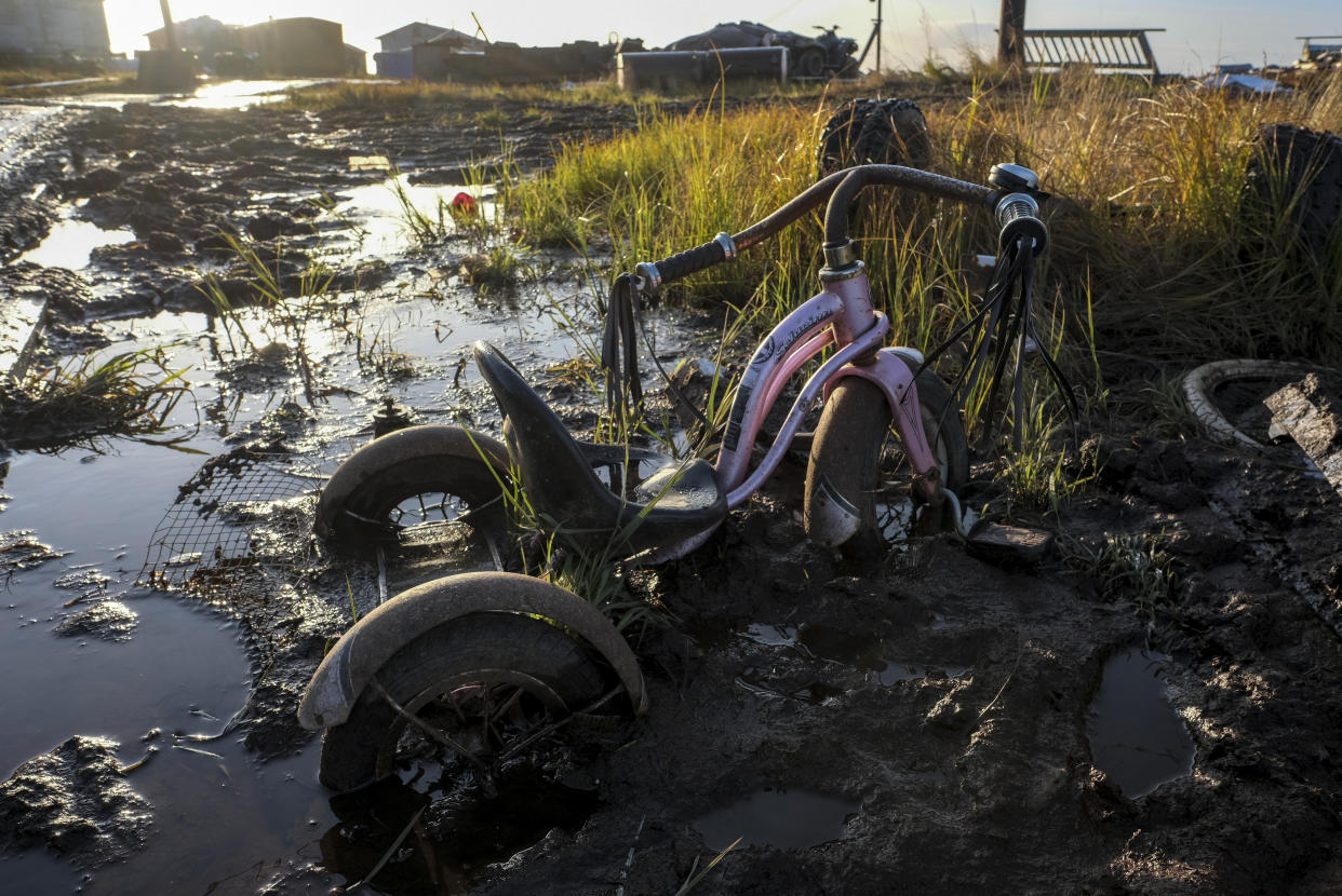 NEWTOK, ALASKA - OCTOBER 8: A child's tricycle sinks in the muck off a boardwalk in Newtok, Alaska on October 8, 2019. Thawing permafrost creates a wet and ever-shifting environment in the village. (Photo by Bonnie Jo Mount/The Washington Post via Getty Images)