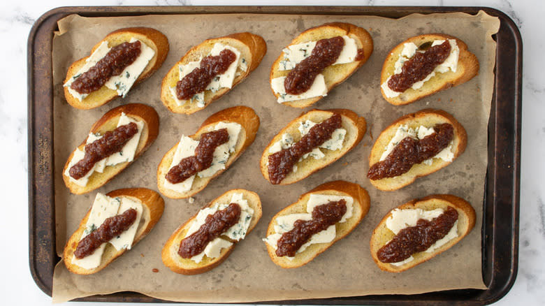 crostini with cheese and jam on baking sheet