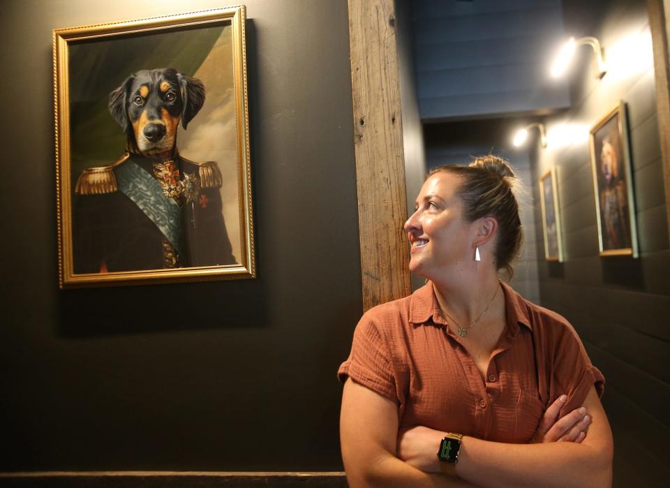 Kiersten Mayes and her husband John Ernst love their dogs. Kiersten glances at a portrait of their dog, Teddy, and there are two more on the walls to the bathroom of their new eatery, The Bar Next Door in York.