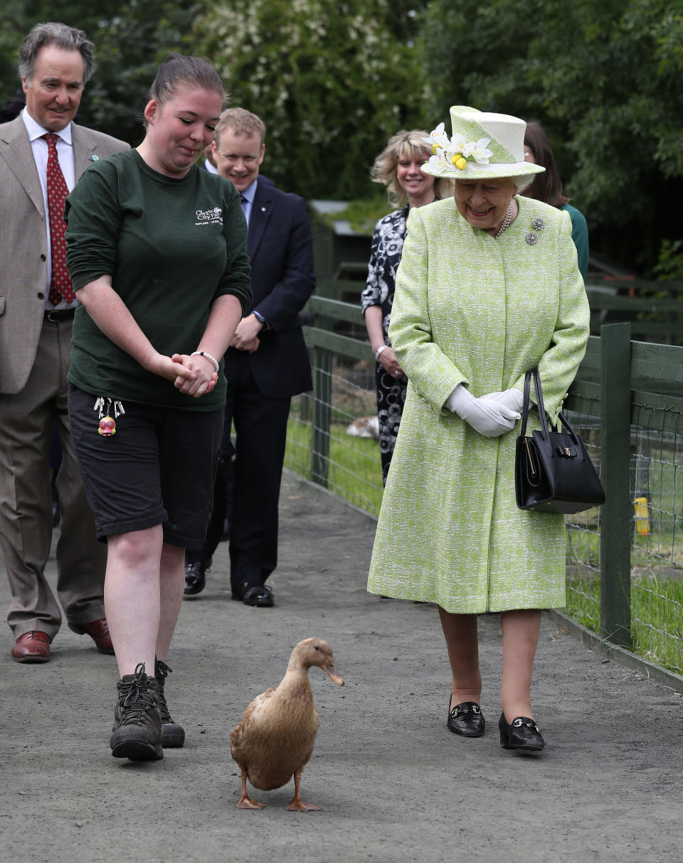 Queen Elizabeth II with keeper Maia Gordon as Olive the duck walks alongside them during a visit to Gorgie City Farm in Edinburgh.