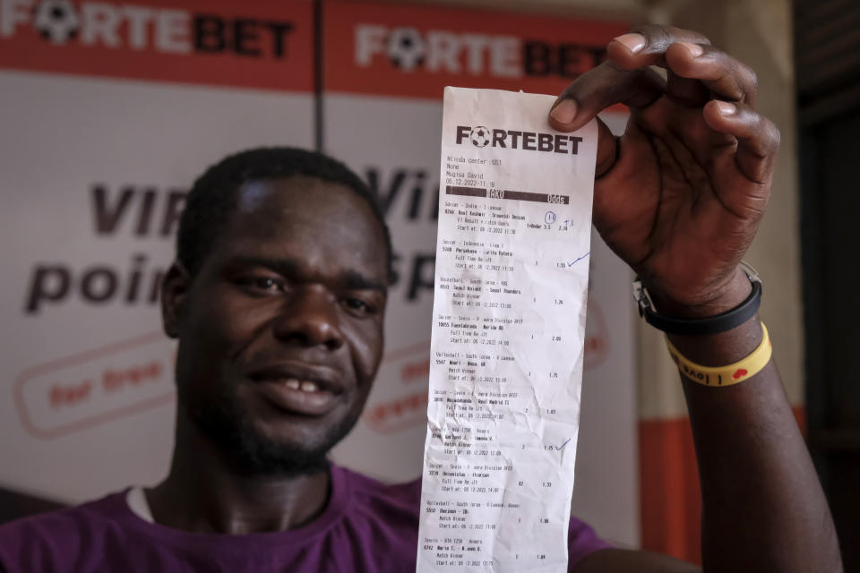 Gideon Matua looks at his betting slip at the Fortebet sports betting centre in Ntinda, Kampala. at the Fortebet sports betting shop in the Ntinda area of the capital Kampala, Uganda, Tuesday, Dec. 6, 2022. Although sports betting is a global phenomenon and a legitimate business in many countries, the stakes are high on the continent of 1.3 billion people because of lax or non-existent regulation, poverty and widespread unemployment. (AP Photo/Hajarah Nalwadda)