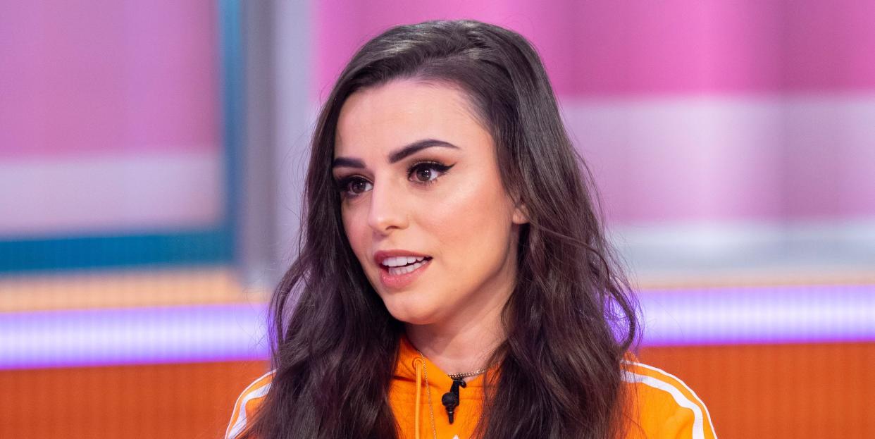 cher lloyd wears her long brown hair down over her shoulders and sports a bright orange sports jumper